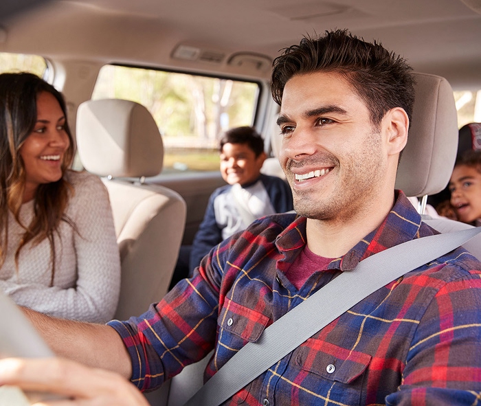 Familia de cuatro integrantes sonriendo en un automóvil