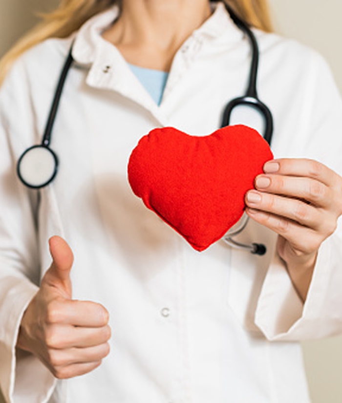 Doctor holding a red heart and giving thumbs up