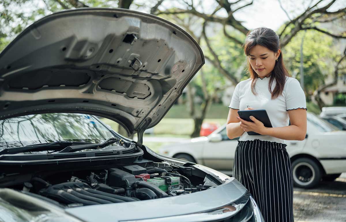 Woman writing up a claim next to a car.