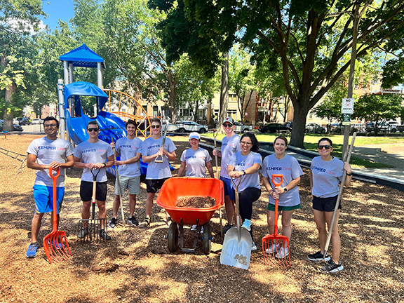 Empleados de Kemper trabajando en un parque infantil con palas y una carretilla 