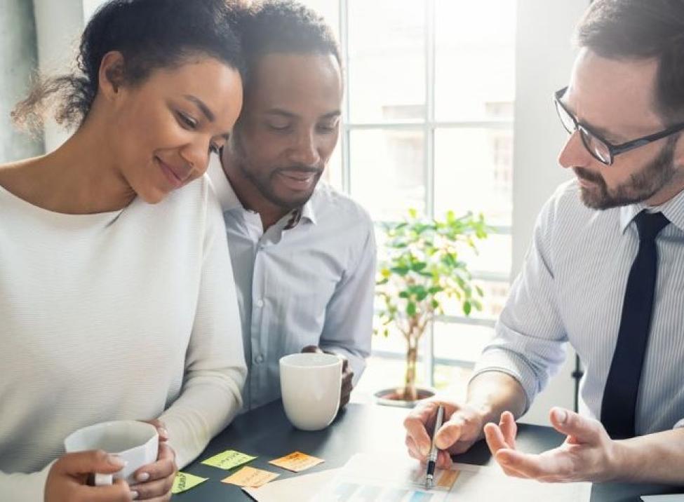 Photo: a smiling couple is reviewing life insurance options with their agent.