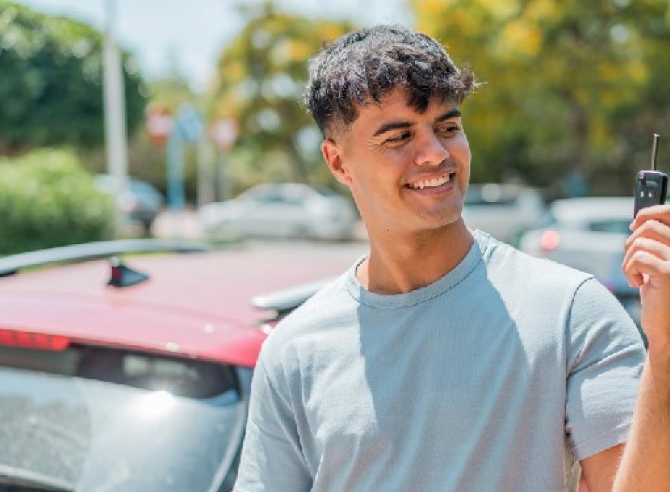 Photo of a young man with car insurance holding up the key to his car