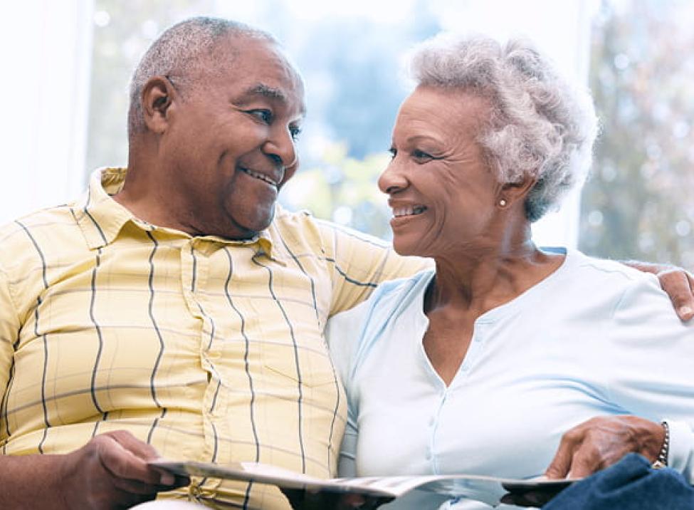 Elderly couple smiling at each other while reading about insurance